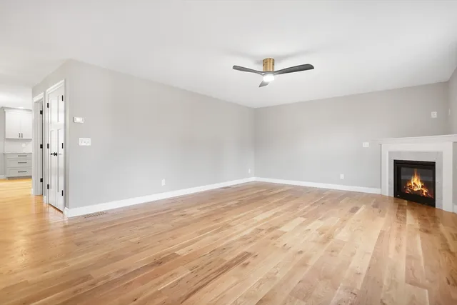 a view of empty room with wooden floor and fireplace