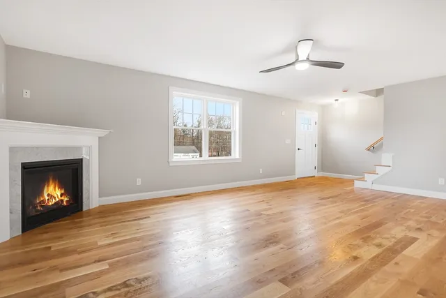 a view of an empty room with wooden floor fireplace and a window