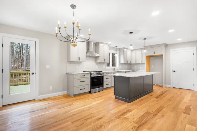 a kitchen with stainless steel appliances granite countertop a refrigerator a sink dishwasher a stove and white cabinets with wooden floor