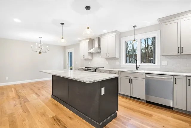 a kitchen with stainless steel appliances granite countertop a sink a stove and a wooden floors