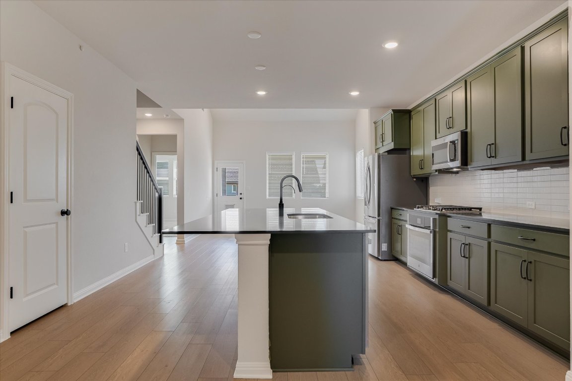 168 Kings Cyn Drive Dripping Springs, TX 78620 - Photo 4 of 25 a kitchen with stainless steel appliances granite countertop a sink a stove top oven a refrigerator with wooden floors