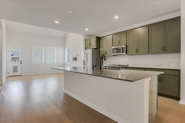 a large kitchen with stainless steel appliances granite countertop a large counter top a sink and a refrigerator