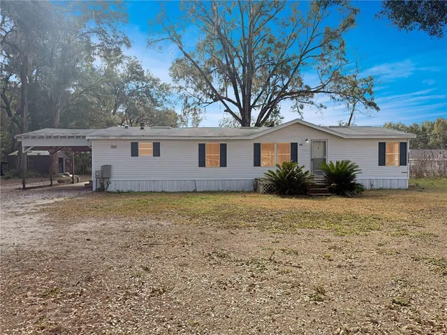 a front view of house with yard and trees around