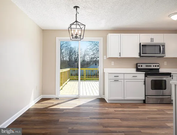 a view of a kitchen with wooden floor electronic appliances and windows