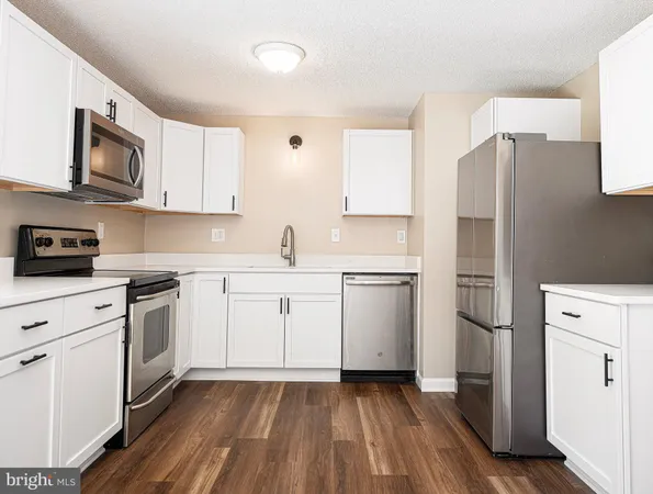 a kitchen with cabinets stainless steel appliances and wooden floor