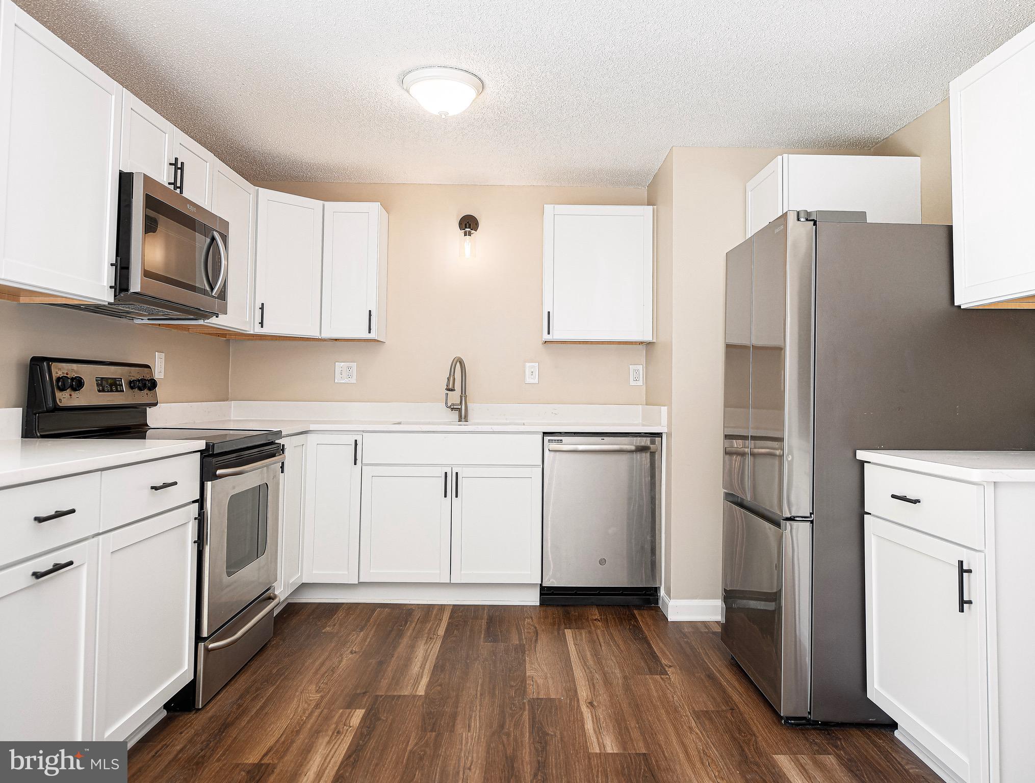1811 Cape May Road Essex, MD 21221 - Photo 9 of 34 a kitchen with cabinets stainless steel appliances and wooden floor