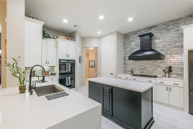 a kitchen with stainless steel appliances a sink a stove a refrigerator and cabinets