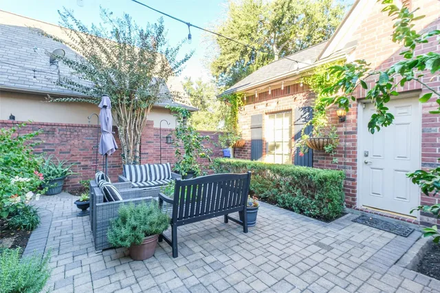 a view of a brick house with a small yard and a large tree