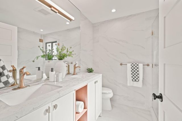 a bathroom with a granite countertop sink mirror vanity and toilet