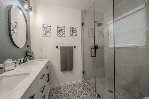 a bathroom with a double vanity sink mirror and shower