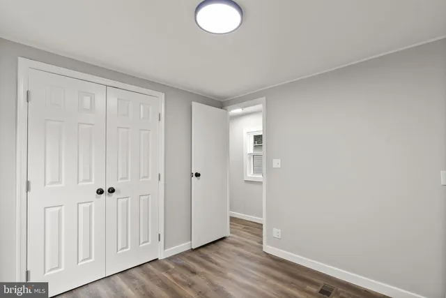 an empty room with wooden floor and closet area