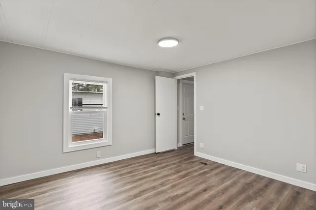 a view of an empty room with window and wooden floor