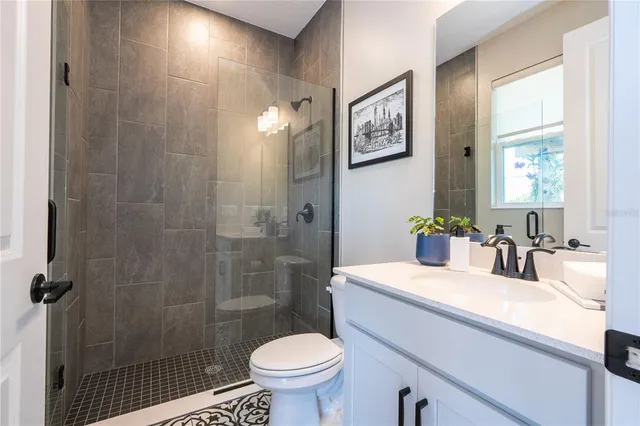 a bathroom with a granite countertop sink a toilet and shower