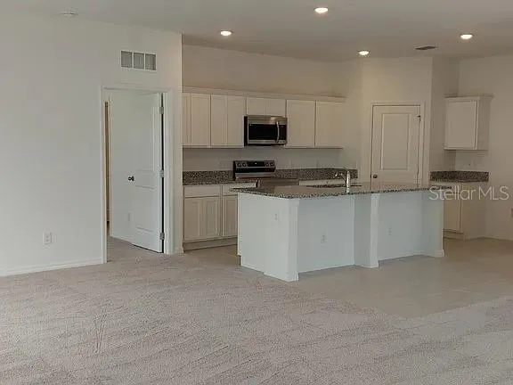 a kitchen with stainless steel appliances granite countertop a stove top oven a sink and a refrigerator