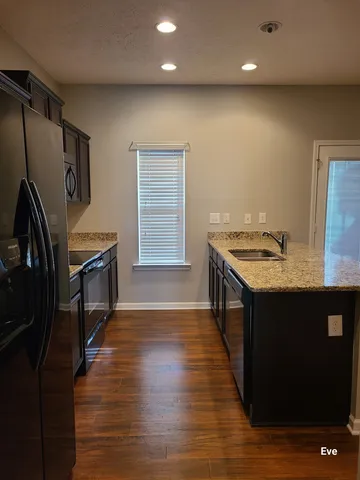 a kitchen with stainless steel appliances granite countertop a sink a stove and a wooden floors