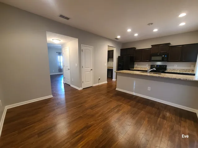 a view of kitchen with stainless steel appliances a sink and wooden floor