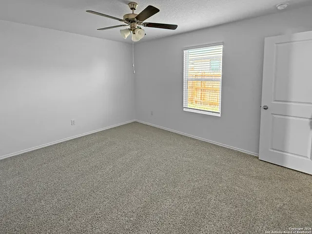 an empty room with a window and a fan