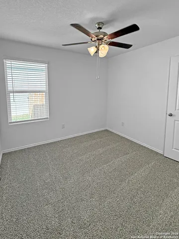 an empty room with a window and a fan