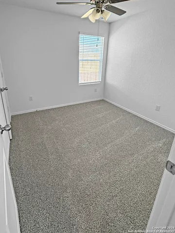 an empty room with a chandelier fan and windows