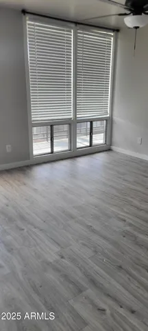 an empty room with wooden floor and windows