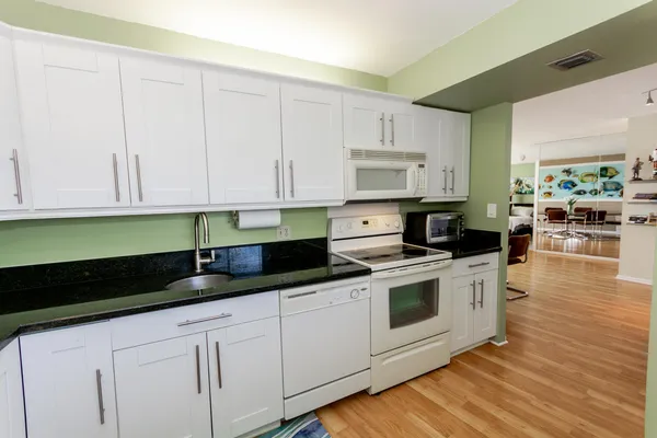 a kitchen with granite countertop white cabinets and white appliances