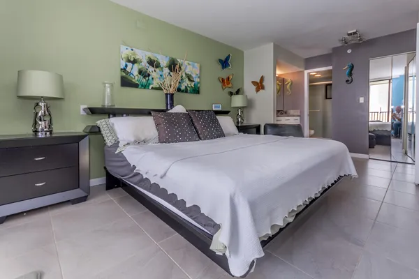 a spacious bedroom with a bed and a lamp on dresser