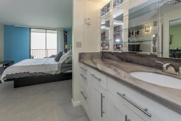 a bedroom with a bed and a large mirror next to a window