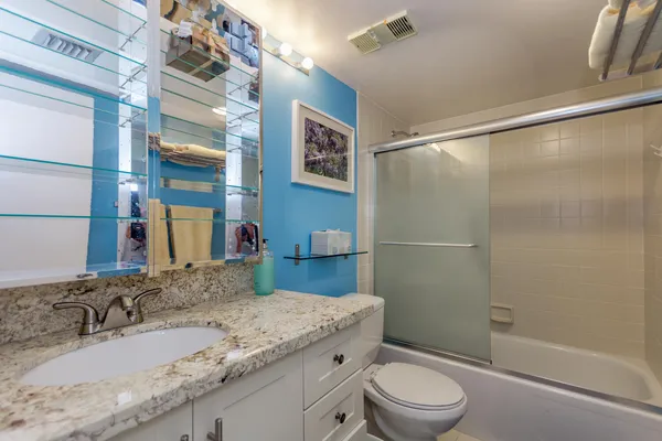 a bathroom with a granite countertop sink toilet and shower