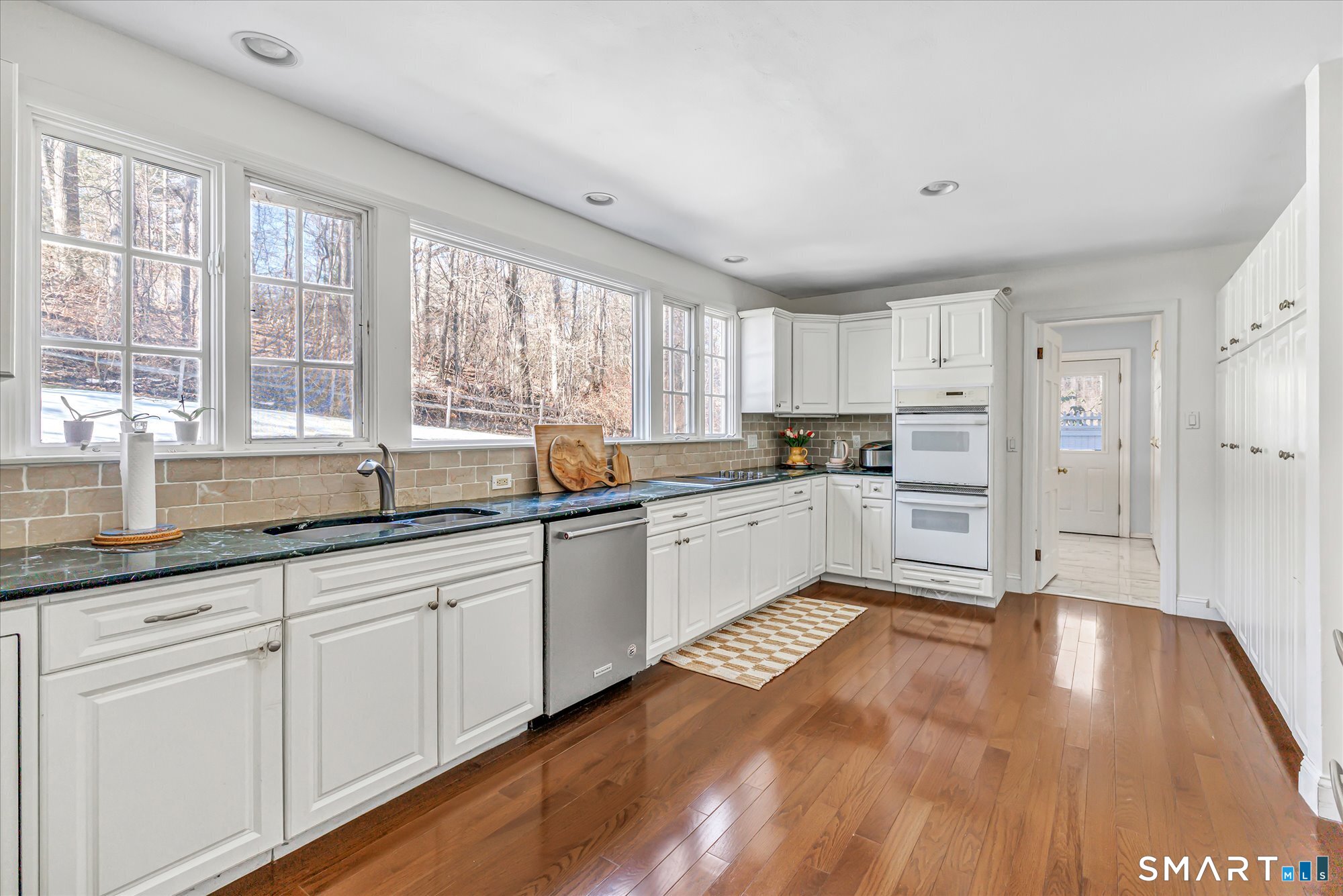 39 Marion Road Westport, CT 06880 - Photo 17 of 46 a kitchen with granite countertop a stove a sink and white cabinets with wooden floor