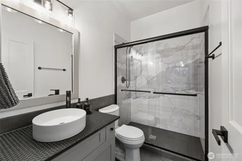 a bathroom with a granite countertop sink mirror vanity and toilet