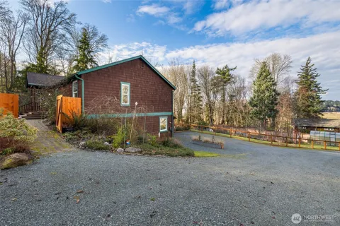 a view of a house with large trees next to a road