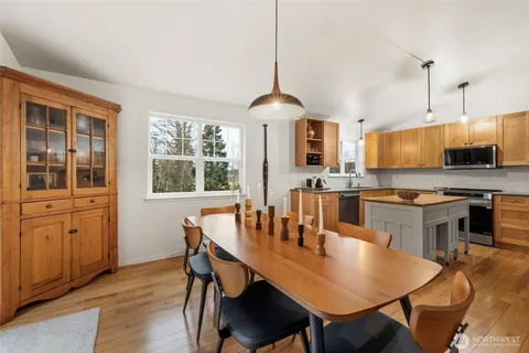 a kitchen with stainless steel appliances granite countertop a stove a refrigerator a kitchen island a table and chairs
