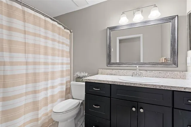 a bathroom with a granite countertop sink a toilet and a mirror