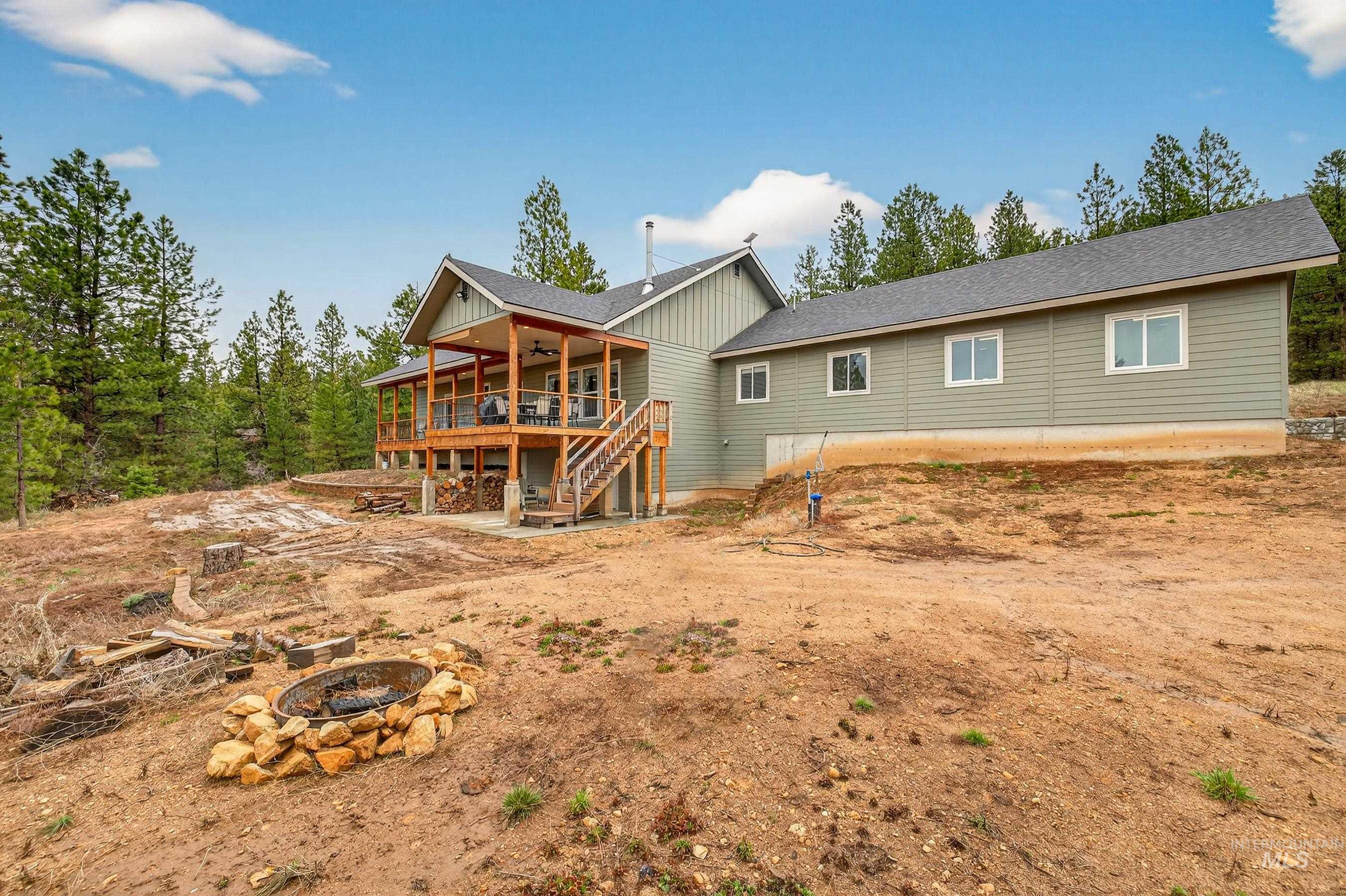 10191 Timberrim Drive Cascade, ID 83611 - Photo 5 of 44 Back of house featuring a ceiling fan, a wooden deck, roof with shingles, an outdoor fire pit, and a patio