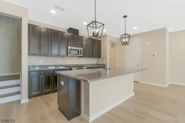 a kitchen that has a sink stainless steel appliances and cabinets