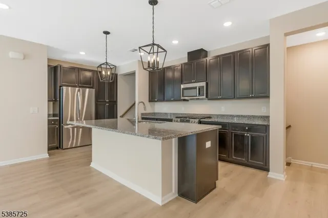 a kitchen with kitchen island a counter space a sink appliances and cabinets