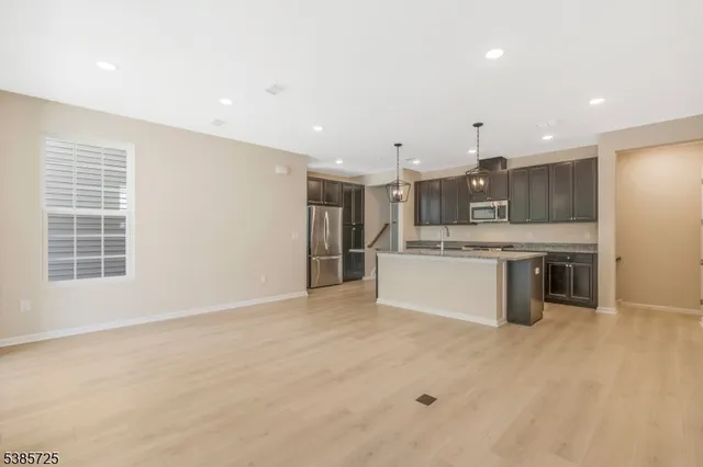 a large kitchen with a large counter top a sink stainless steel appliances and cabinets