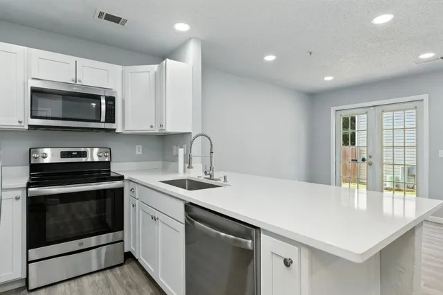 a kitchen with stainless steel appliances white cabinets and sink
