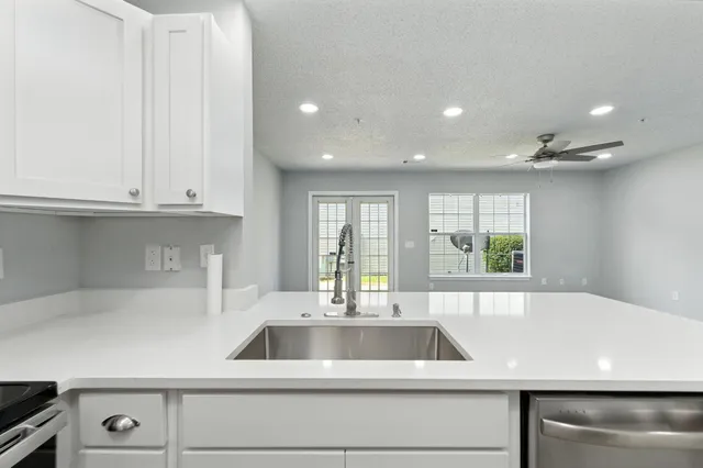 a kitchen with granite countertop a sink and white cabinets
