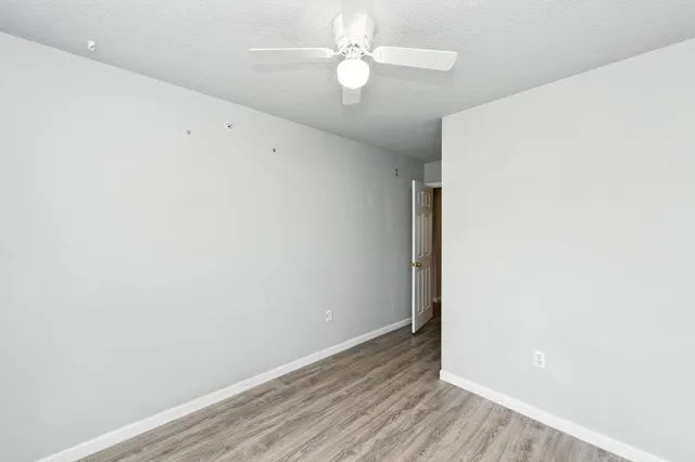 an empty room with wooden floor and fan