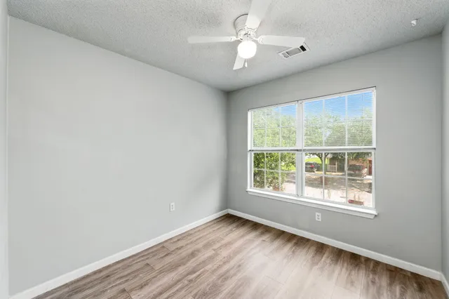 a view of an empty room with a window and wooden floor