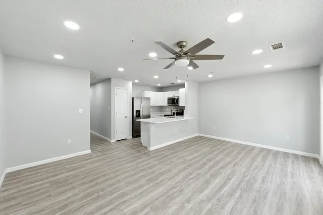 an empty room with wooden floor and a kitchen
