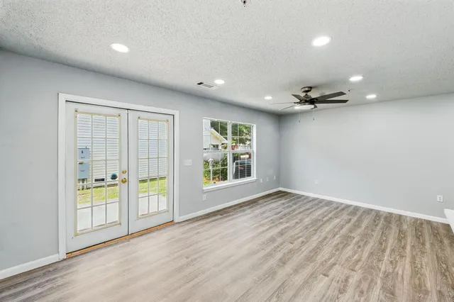 a view of an empty room with a window and wooden floor
