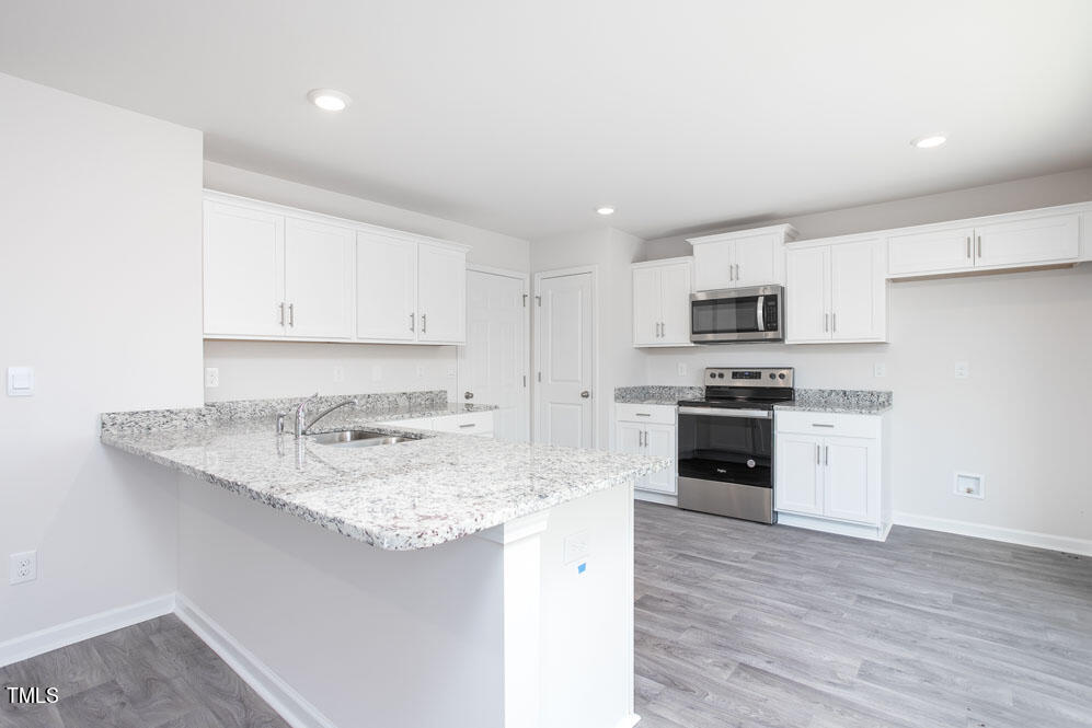 6024 Howth Way Raleigh, NC 27610 - Photo 11 of 22 a kitchen with kitchen island granite countertop a sink cabinets and stainless steel appliances