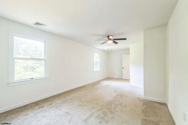 an empty room with a chandelier fan and windows