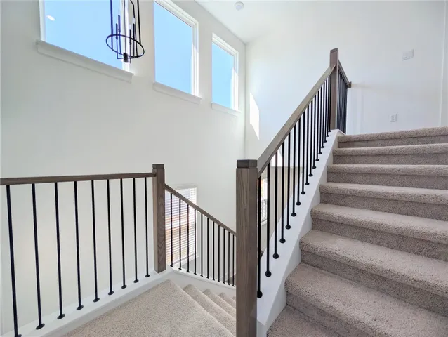 a view of staircase with lots of frames on wall and a window