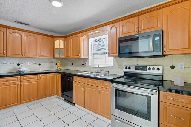 a kitchen with stainless steel appliances granite countertop a refrigerator and a sink