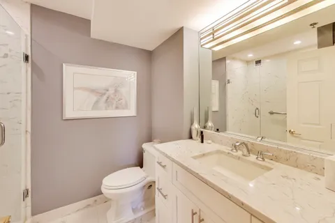 a bathroom with a granite countertop sink mirror vanity and toilet