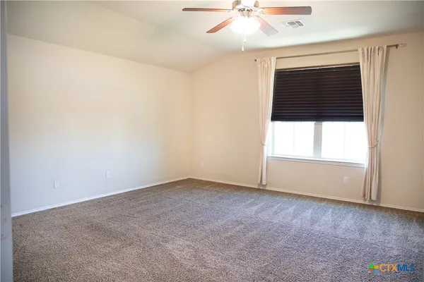 an empty room with a ceiling fan and window