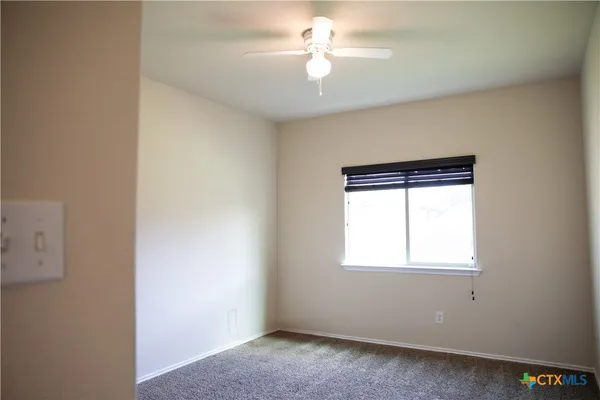 an empty room with a window and a fan